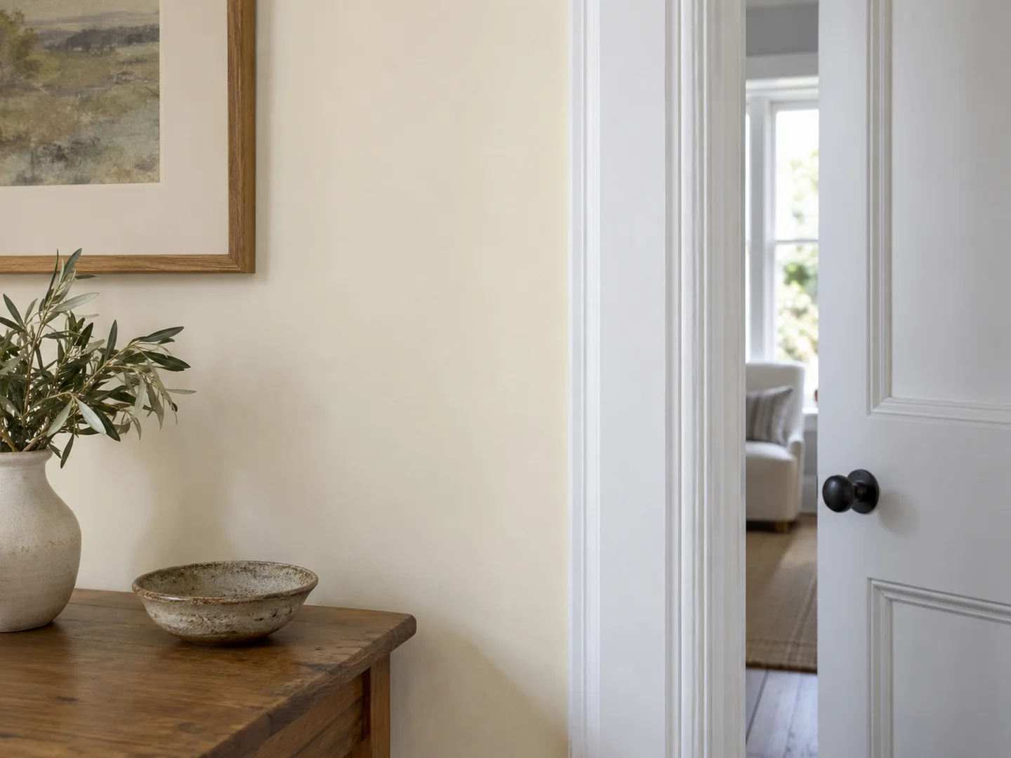 warm ivory painted wall beside a cooler white door frame, neutral interior detail.