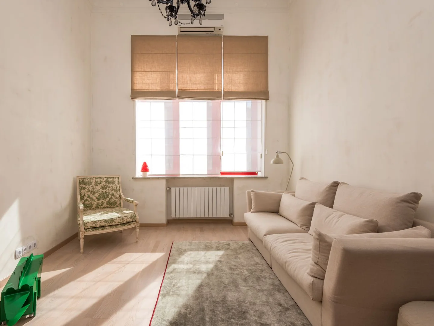 A beige sofa and a separate armchair in a narrow room, with open floor between the seats.