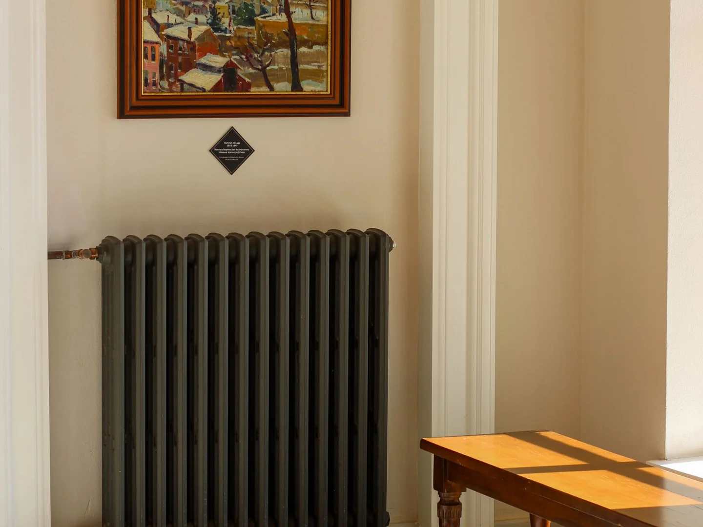An uncovered dark radiator against a pale wall.