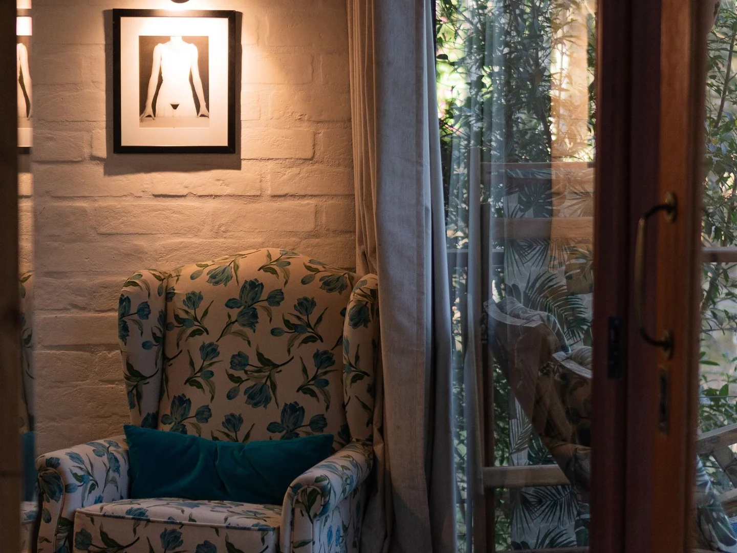A patterned armchair beneath a reading light.