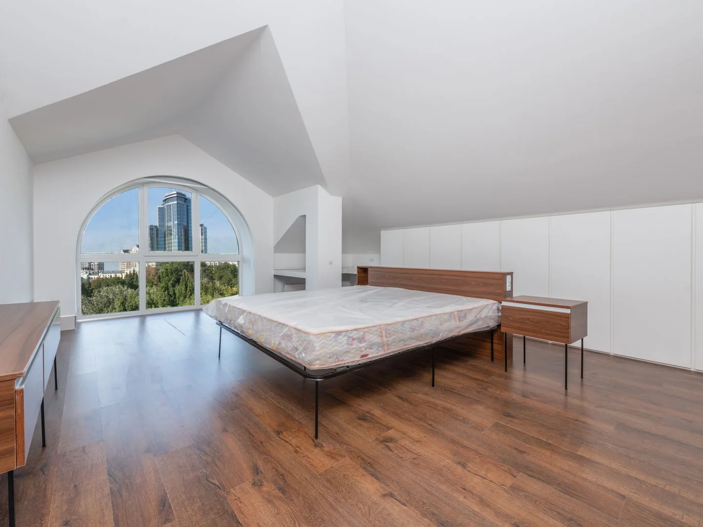 A low bed positioned under a sloping bedroom ceiling.