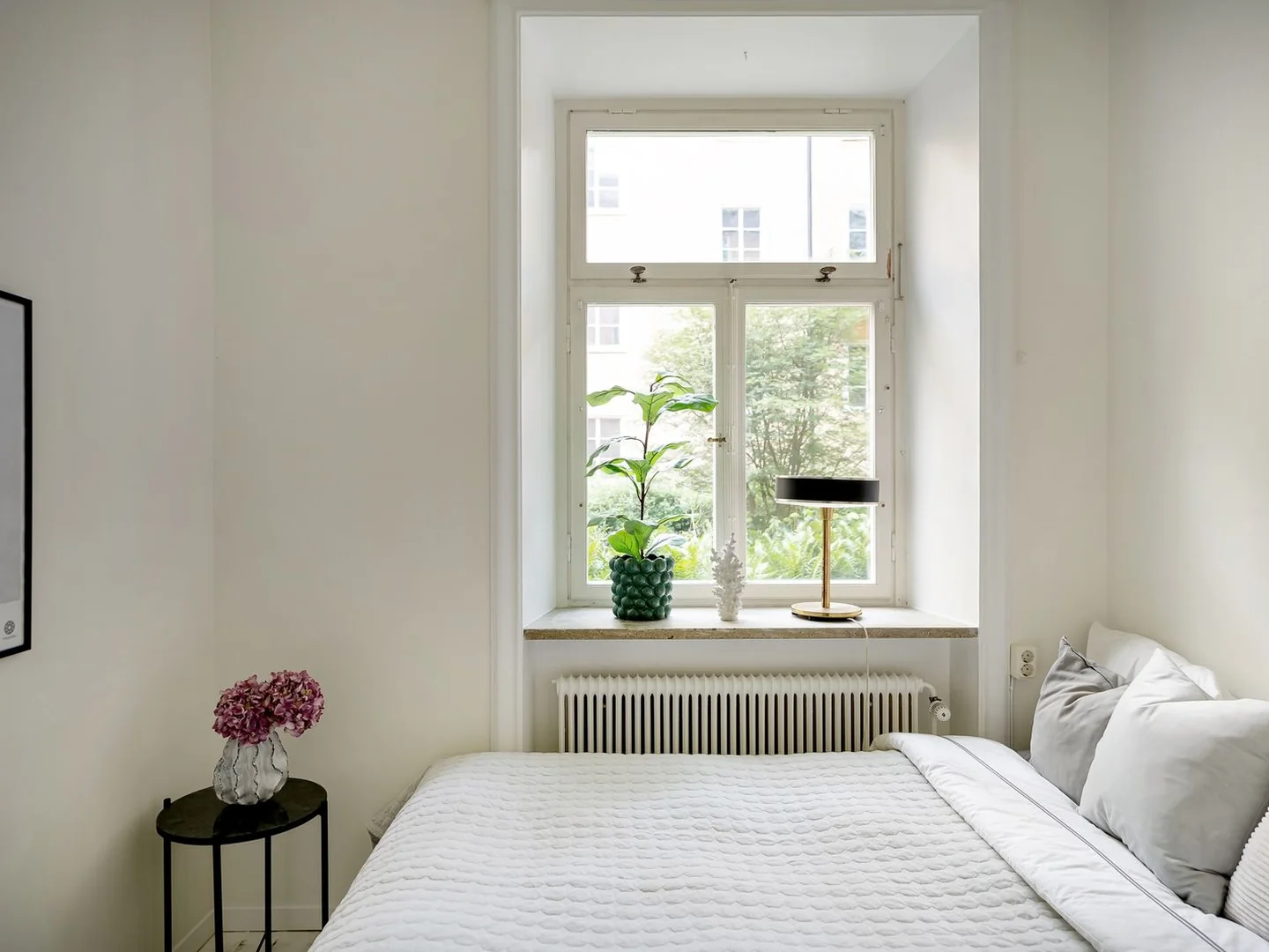 A double bed in a compact room beside a window.