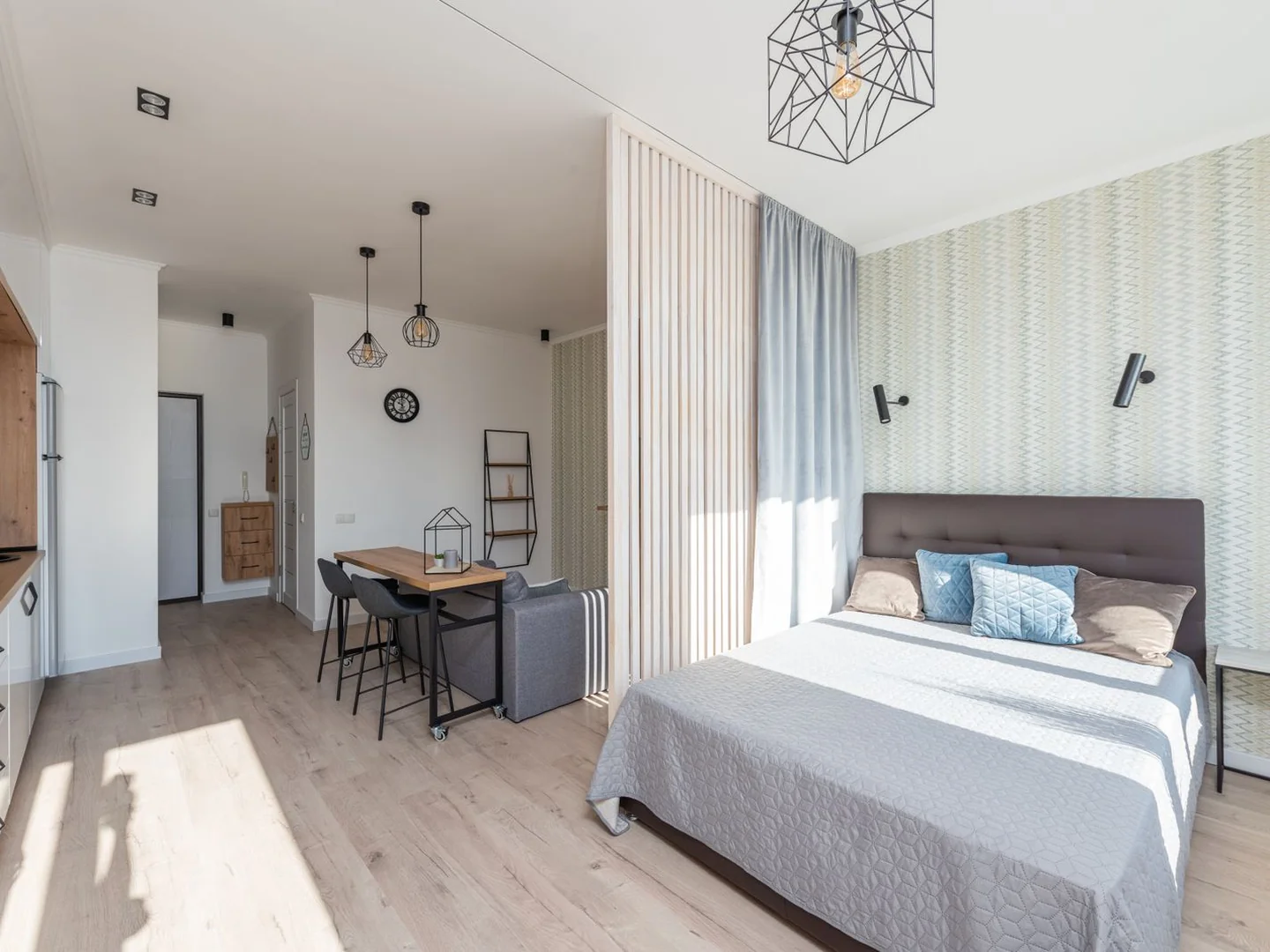 A studio interior with a bed, dining area and kitchen in one room.