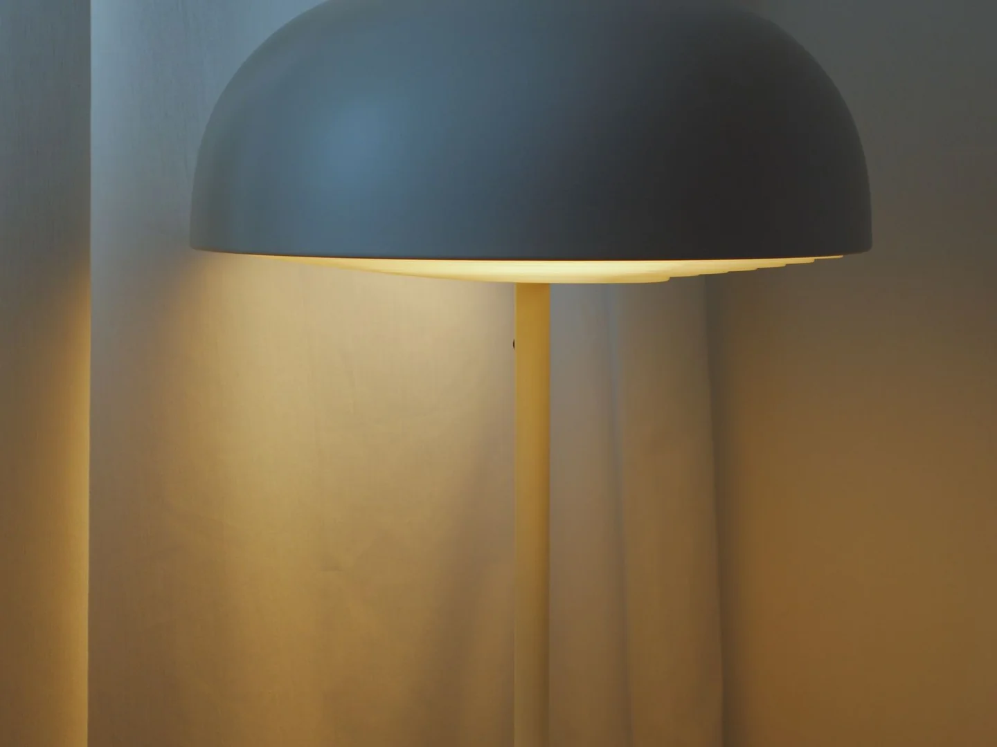 An opaque dome shade above a slim lamp stem on a side table.
