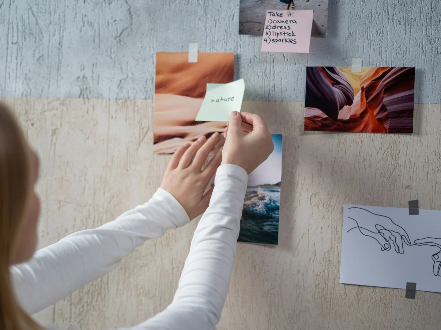 A person arranging notes and visual references on a moodboard.