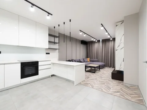 Black pendant fittings and slim dark furniture details in a pale open room.