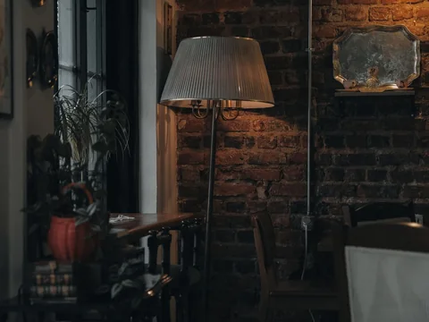 A sitting room lit by a shaded table lamp in the evening.