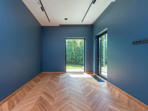 An empty room with blue painted walls above a warm timber floor.