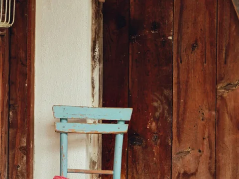 A pale blue wooden chair against warm brown timber.