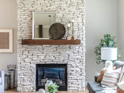 A projecting stone-clad chimney breast between living room furniture.