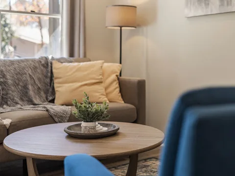 A round coffee table between a sofa and armchair.