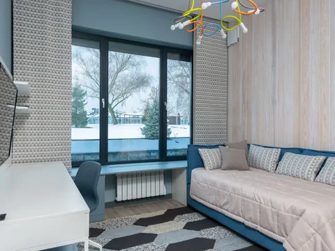 A room combining a sofa with a desk beside the window.