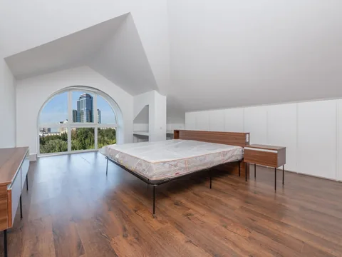 A low bed positioned under a sloping bedroom ceiling.