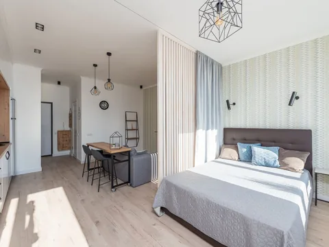 A studio interior with a bed, dining area and kitchen in one room.