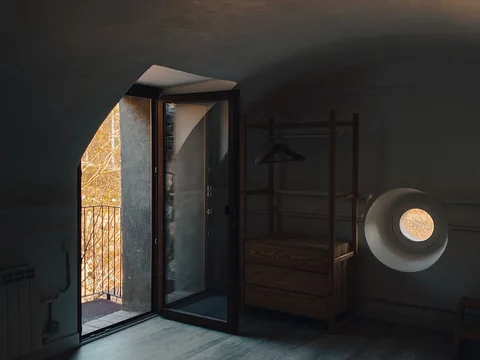 An open door beside a chest in a room with a sloping ceiling.