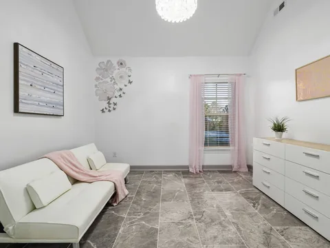 A furnished sitting room with a sofa, chest and window curtains.