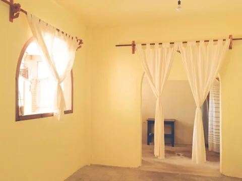 Cream curtains gathered into folds on a pole above a window.