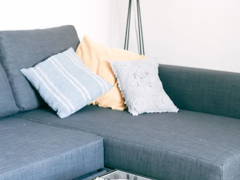 A grey sofa with several different sizes of cushion.
