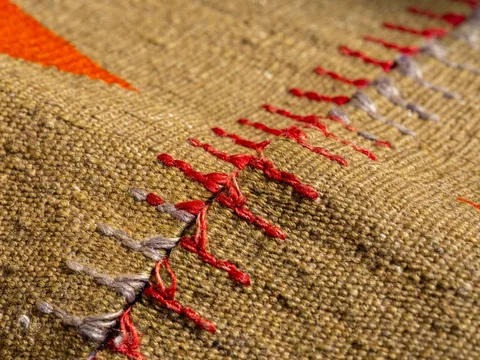A close view of the low woven surface and coloured threads of a rug.